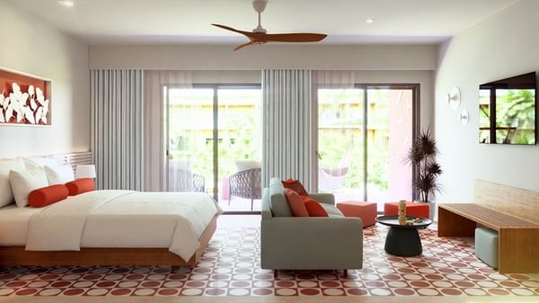 Junior Suite Pool Level espaciosa con sofá gris y balcón tropical en Fiesta Americana Funeeq Punta Cana