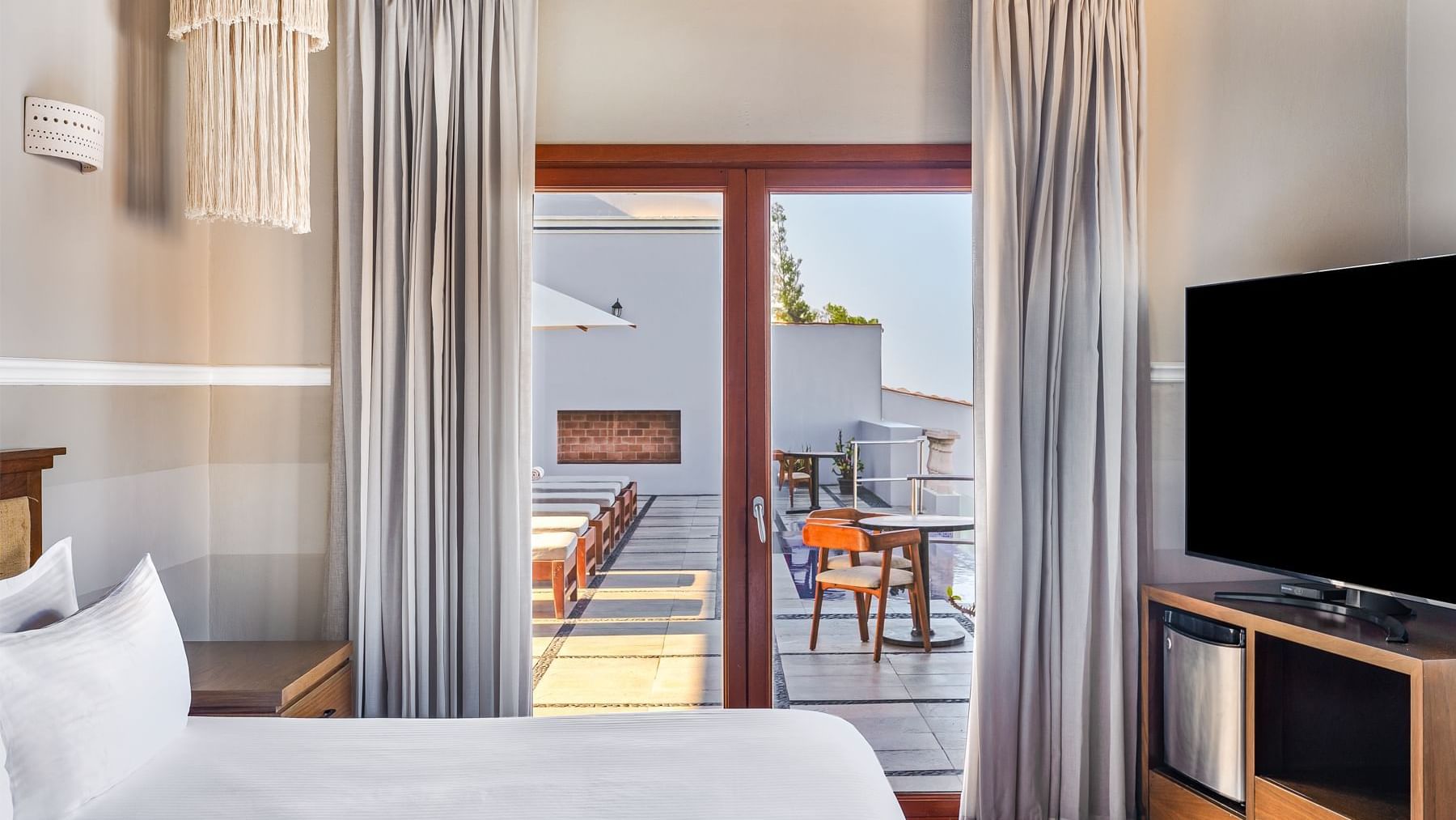 Room with a bed, TV, and large doors leading to an outdoor patio at Curamoria Collection