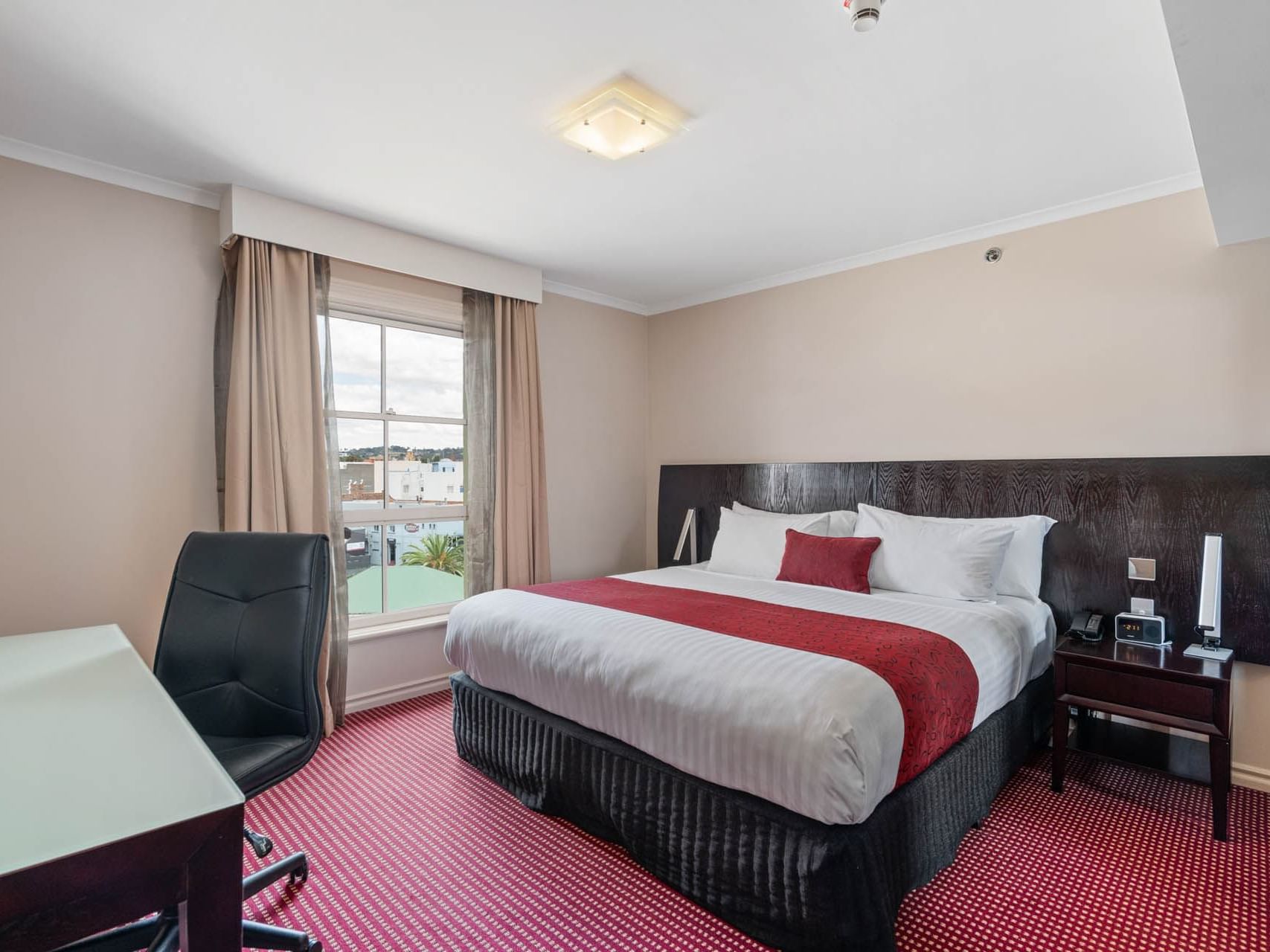 Large bed with side desk and work area in One Bedroom Suite at Hotel Grand Chancellor Launceston
