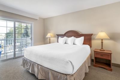 Cozy Pet-friendly Rooms at Ogunquit Hotel and Suites with a plush bed, nightstand, lamp, and balcony access