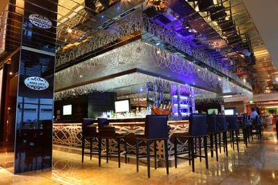 Dark bar stools lined by an ornate counter under hanging beaded decorations in Mamie Lee\'s at Megapolis Hotel Panama