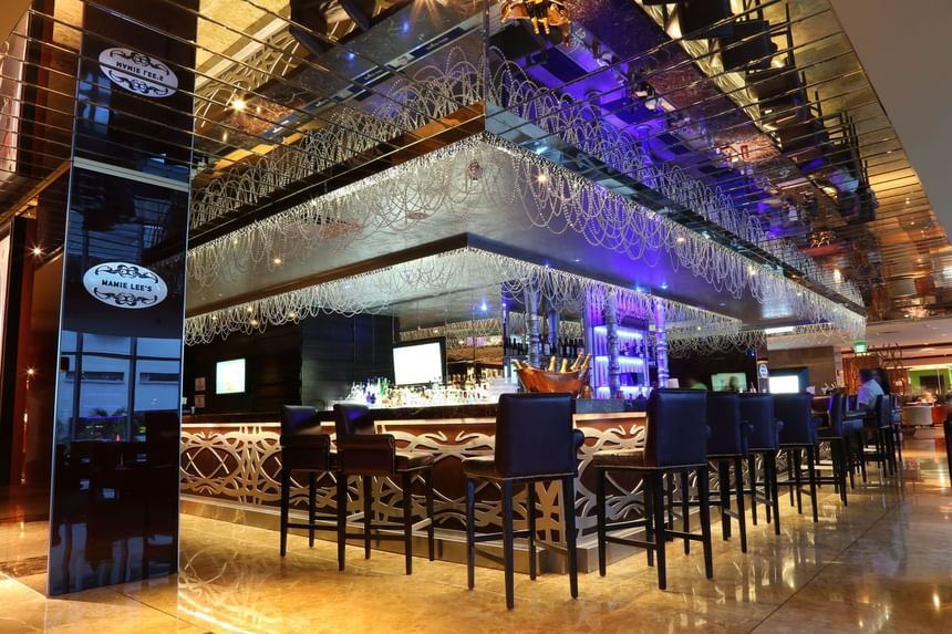 Dark bar stools lined by an ornate counter under hanging beaded decorations in Mamie Lee\'s at Megapolis Hotel Panama