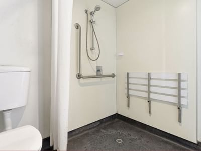 Toilet and shower area with support bars at Student Living Auckland - Beach.