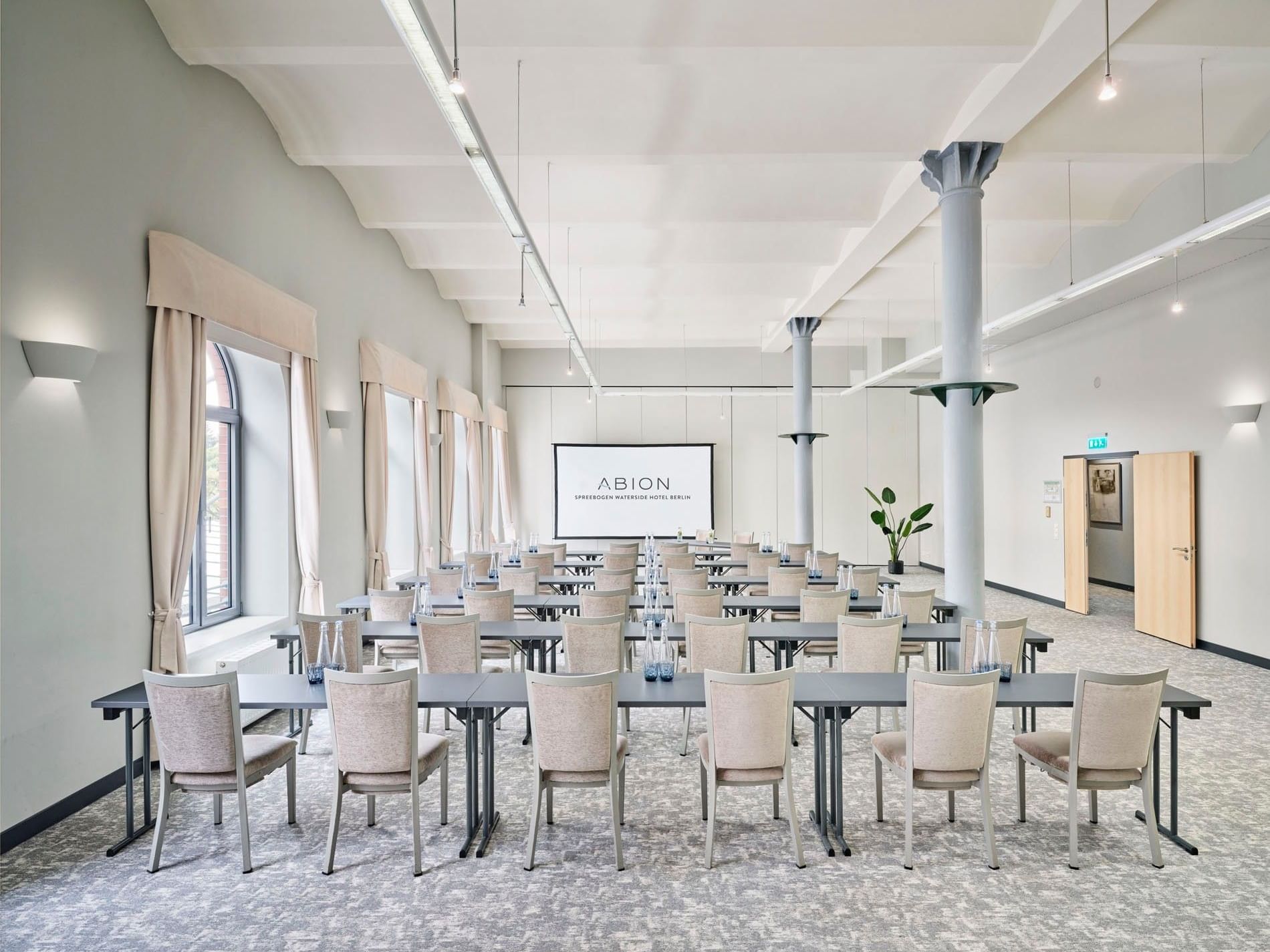 A modern conference room setup with tables and chairs at Abion Spreebogen Waterside Hotel Berlin.