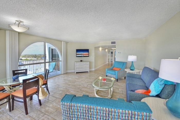 A wide view of a living room and dining area in a suite with a balcony