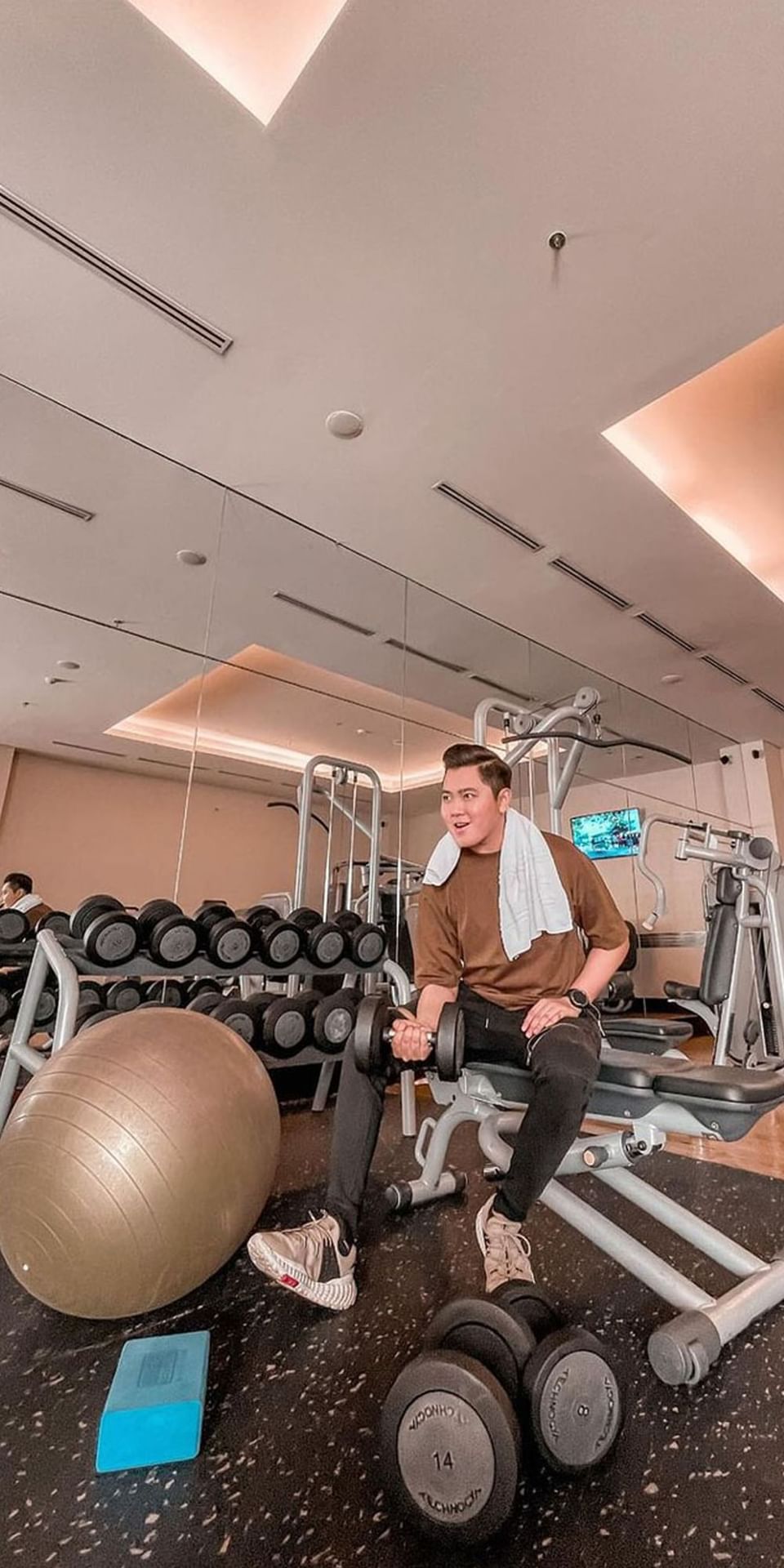 Man sitting on a machine with weights in the Gym at Po Hotel Semarang