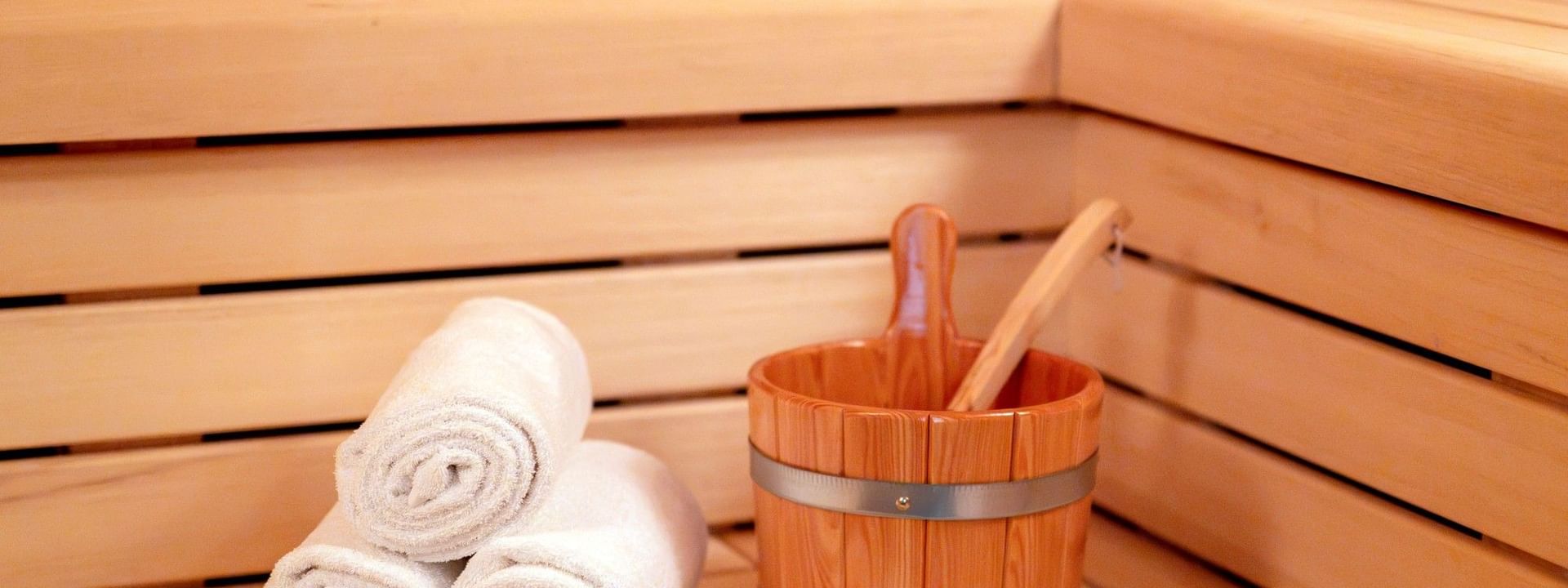 Intérieur de sauna en bois avec serviettes blanches et seau au Warwick Brussels Grand-Place à Bruxelles