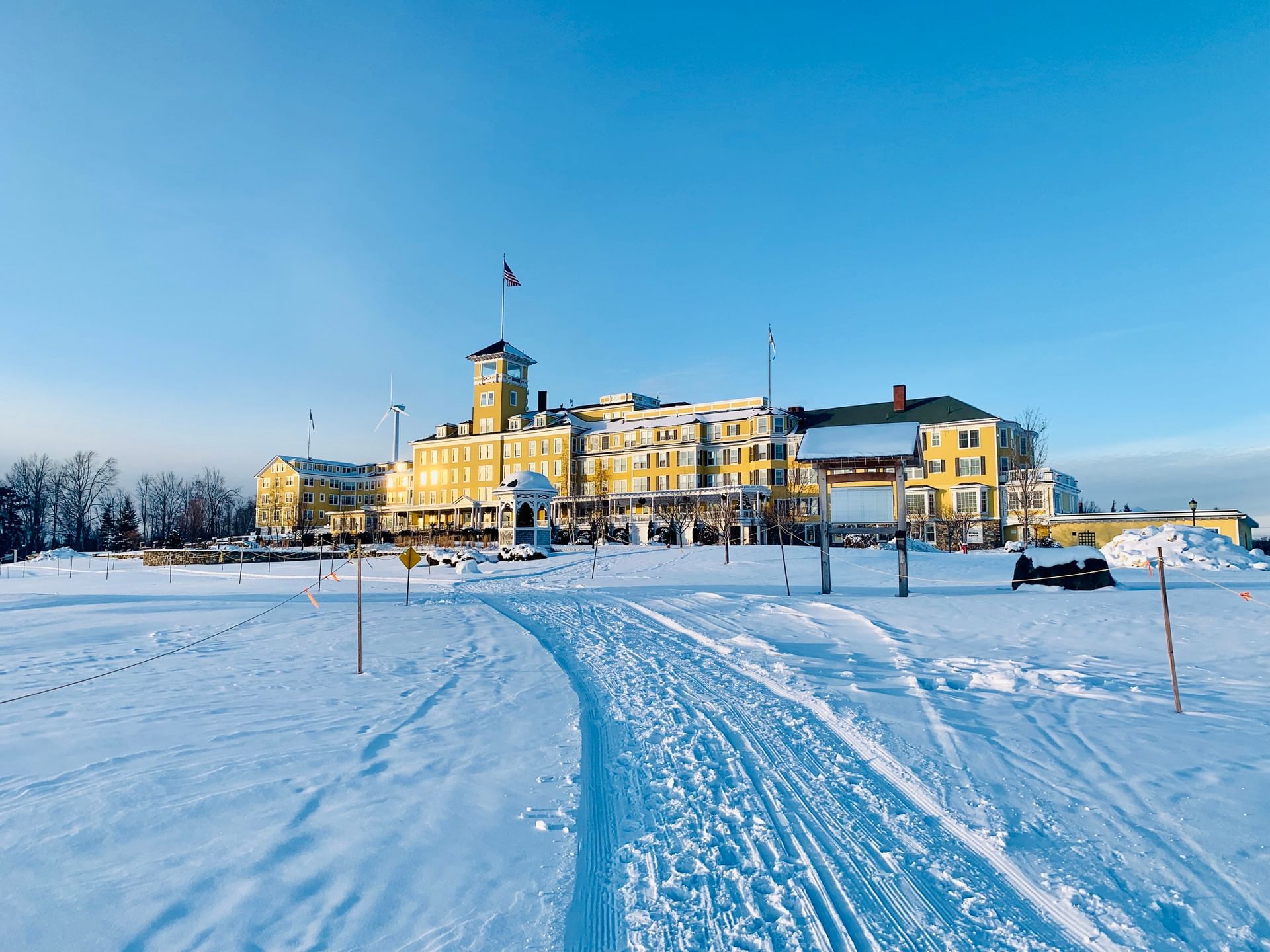 Exterior of Mountain View Grand Resort & Spa, a yellow building beside a groomed ski trail under a clear blue sky
