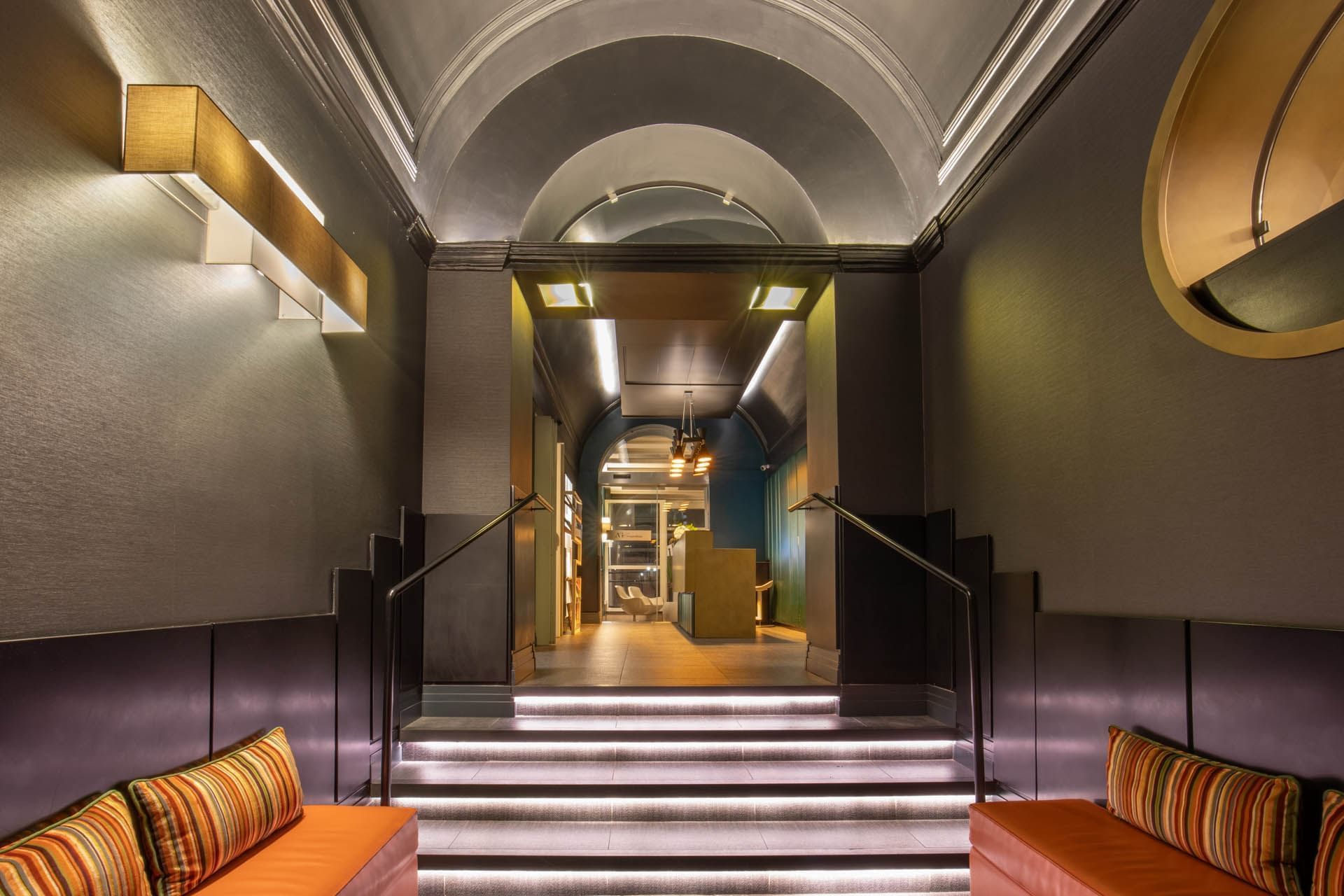 Stylish entrance at The Guardian Hotel with illuminated stairs, sleek walls, and modern decor, leading to a reception area