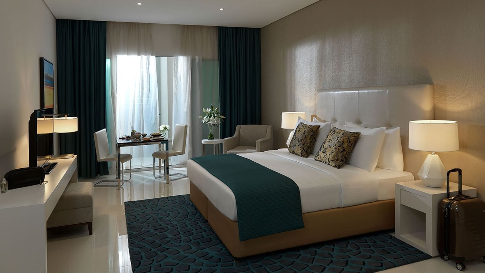 King bed, nightstands & couches with city view in Deluxe Room at DAMAC Maison Cour Jardin