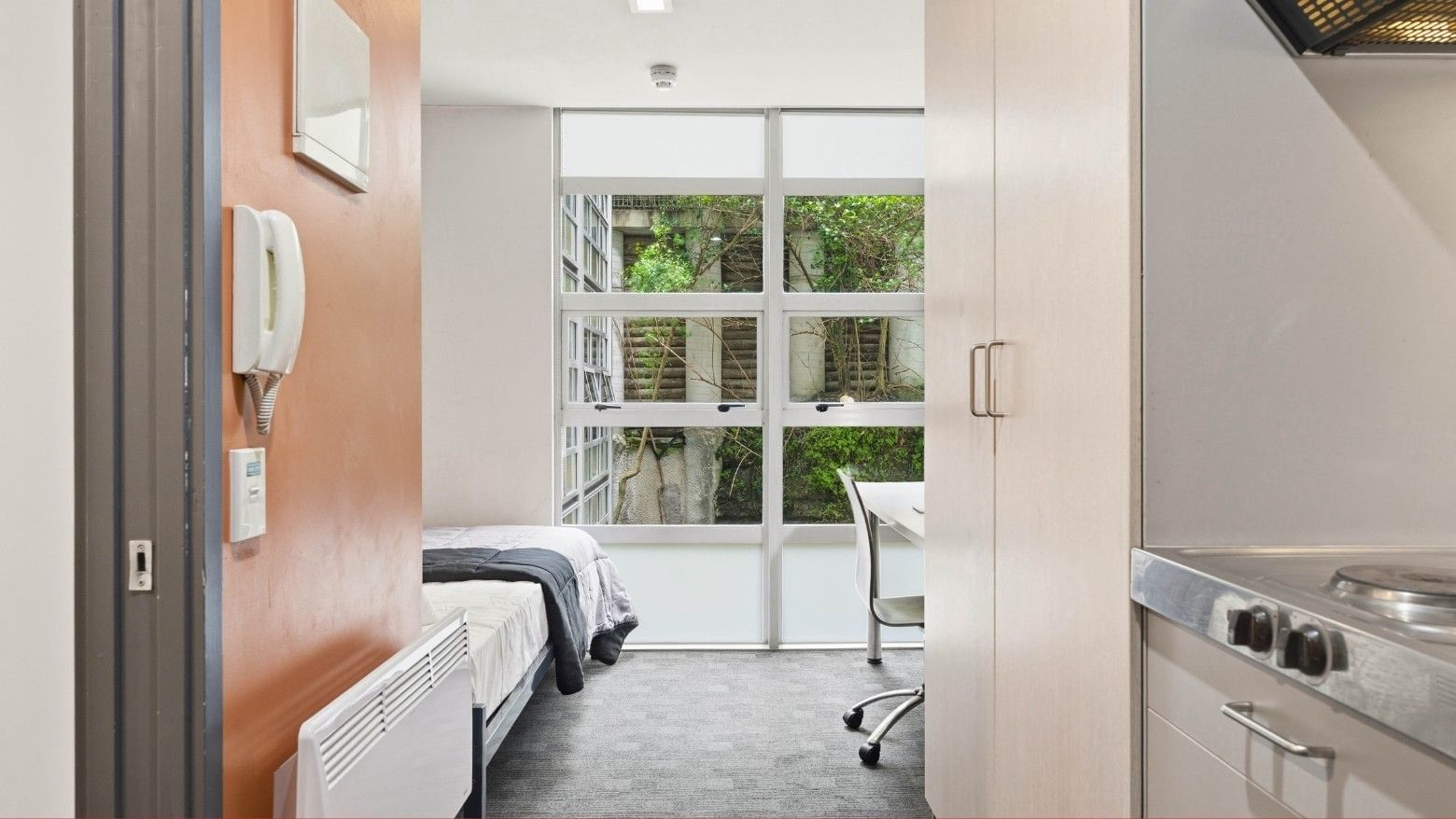 Small room with bed, desk, and kitchen area at Student Living Auckland - Beach.