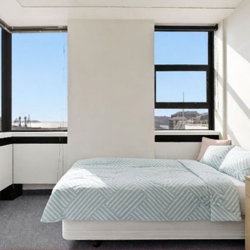 Clean and spacious hotel bedroom with large windows and a cozy bed at UniLodge Stafford House.