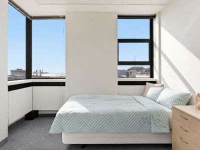 Clean and spacious hotel bedroom with large windows and a cozy bed at UniLodge Stafford House.