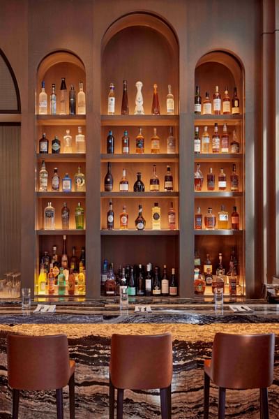 Assorted liquor bottles displayed with a sleek counter in Lobby Bar at Godfrey Hotel Detroit