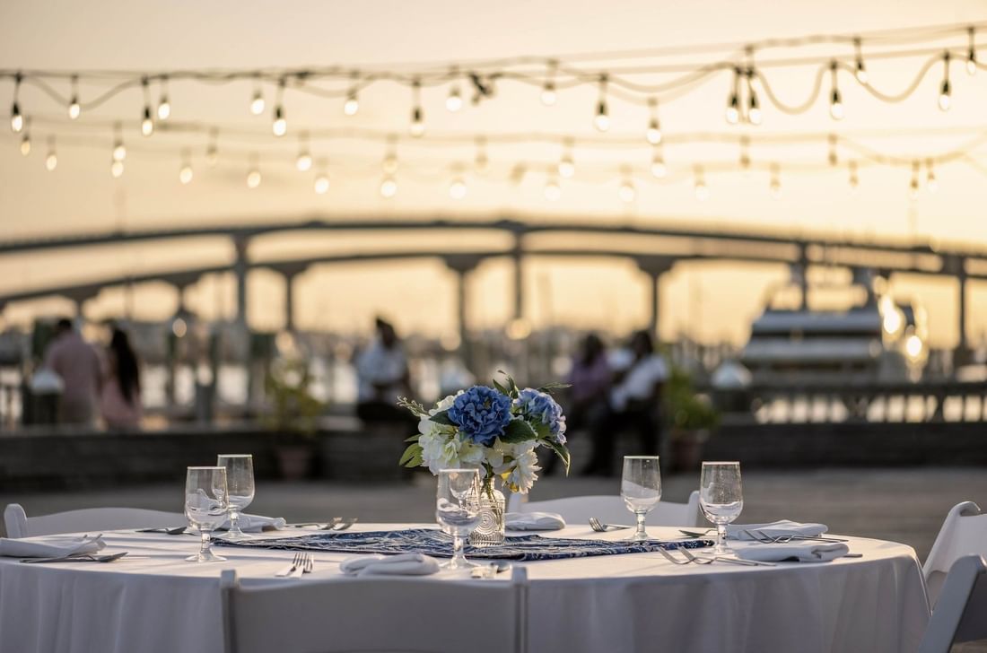 Plated table by a harbor under glowing lights surrounding a bridge at Warwick Paradise Island Bahamas
