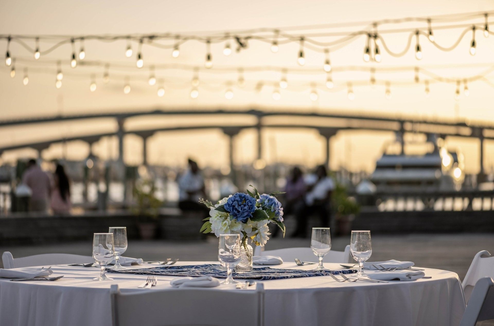 Plated table by a harbor under glowing lights surrounding a bridge at Warwick Paradise Island Bahamas