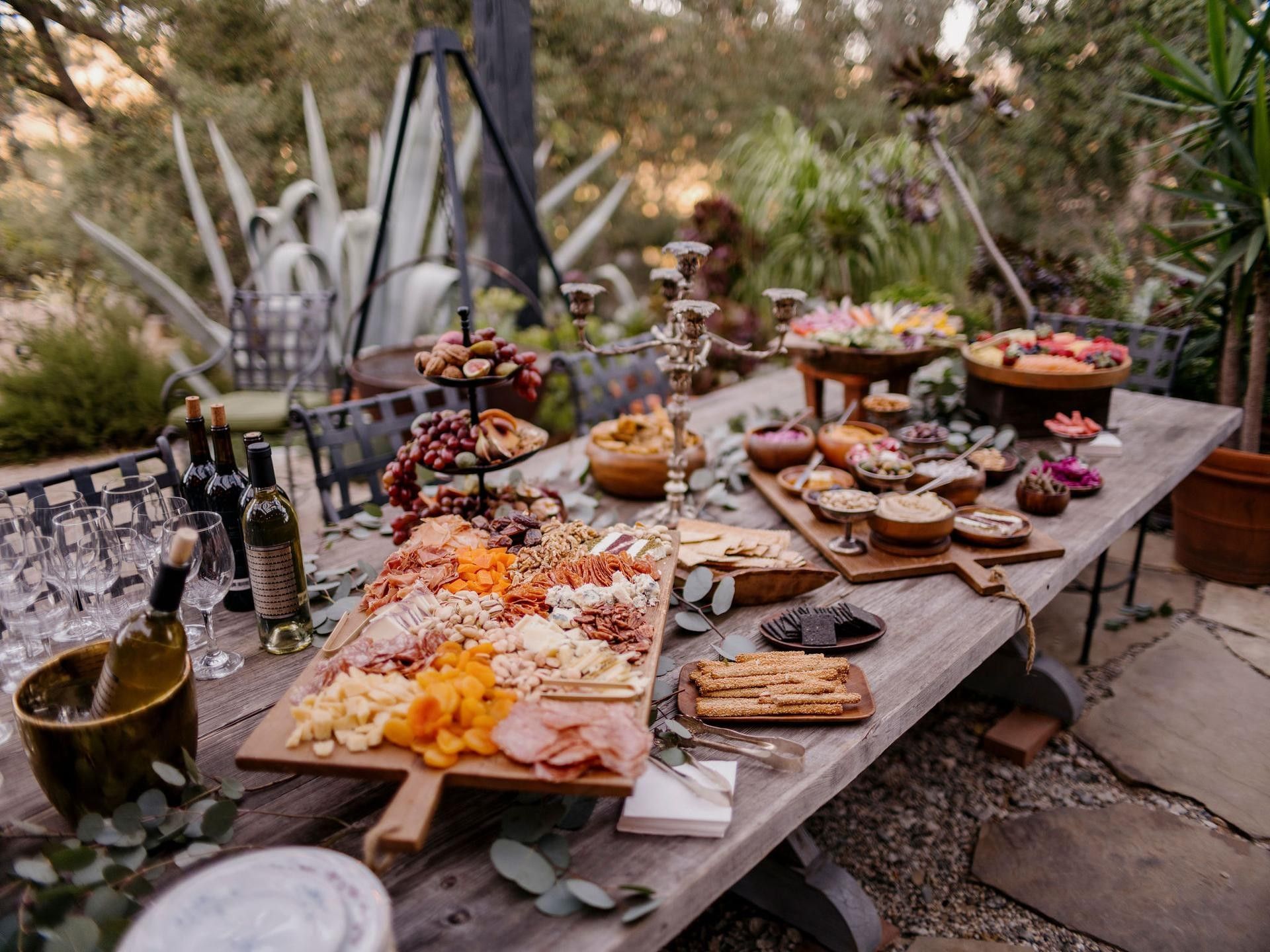 Charcuterie boards with cured meats by wine glasses on a wooden table outdoors in The Villa at Elsewhere Topanga Hotel