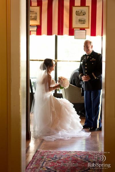 A bride smiling & having a chat with a man at Inn at Saratoga