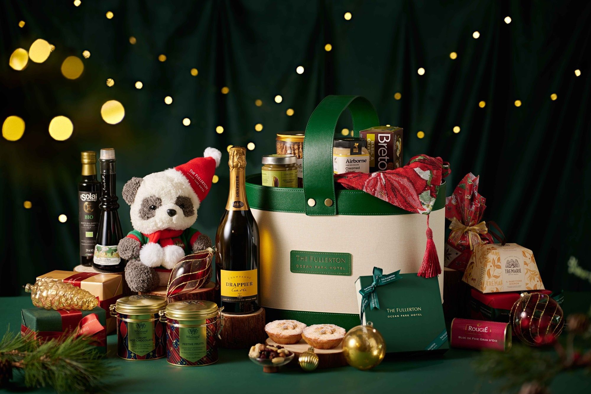 Close-up of a festive hamper with a plush, wine, & gourmet treats among ornaments at Fullerton Ocean Park Hotel Hong Kong