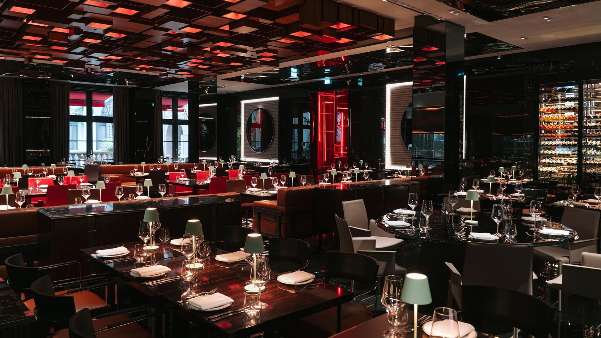 Modern restaurant interior with red and black decor, set tables, and illuminated ceiling panels at Titanic Gendarmenmarkt Berlin