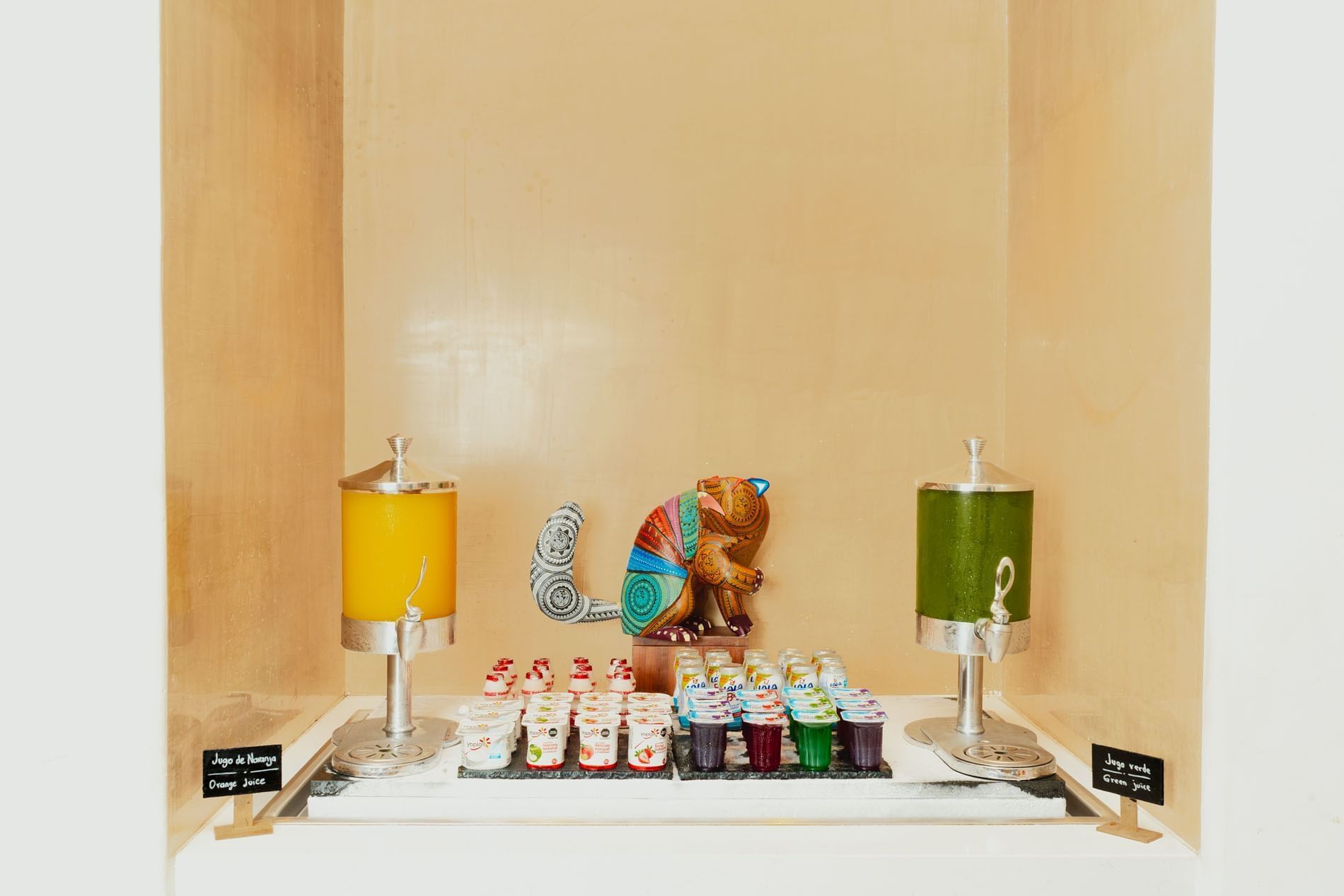 Colorful display of a juice station with dispensers of orange and green juice at Camino Real Zaashila Huatulco