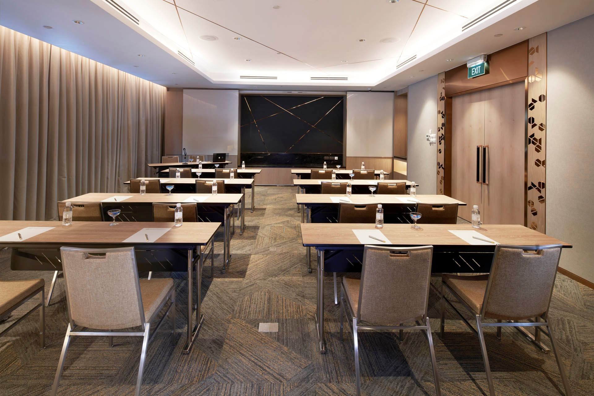 Modern conference room with a classroom table set up and a sleek presentation screen at Orchard Grand Court