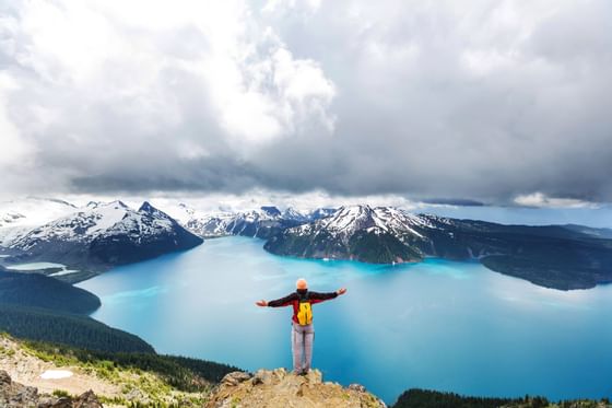 Man standing on top of a mountain under the cloudy sky near Blackcomb Springs Suites