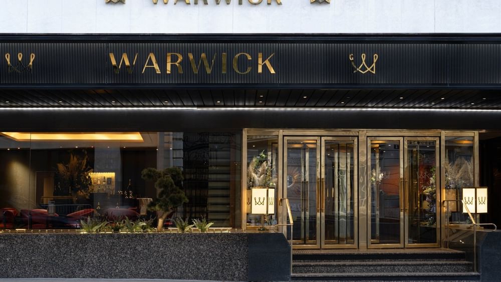 Golden Warwick signs by a black awning under a white facade at Warwick Paris Champs Elysées