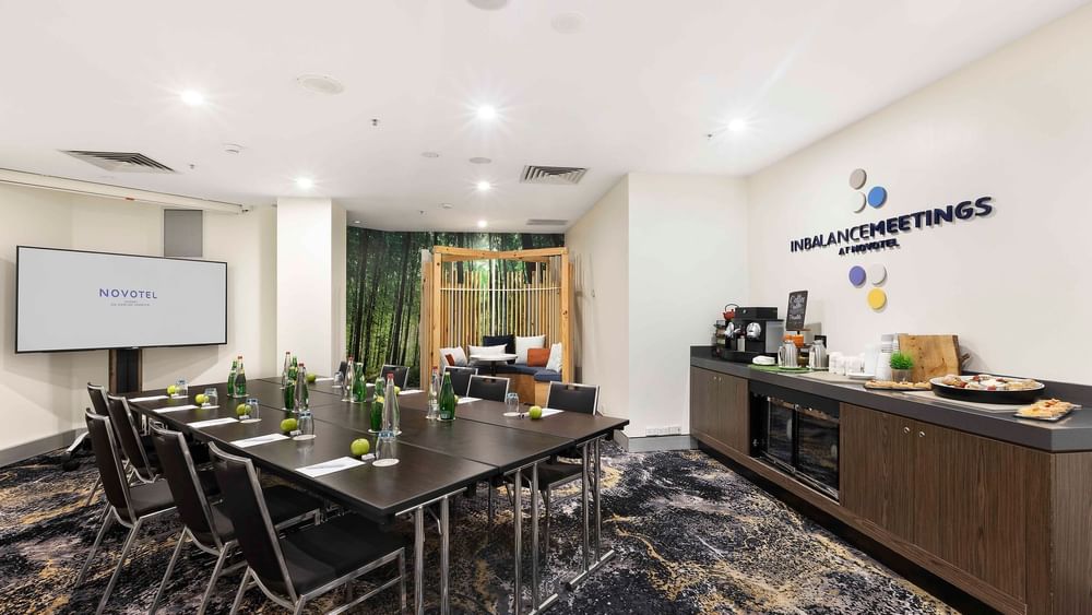 Boardroom set-up facing the projector screen in The McLaren Room at Novotel Sydney on Darling Harbour