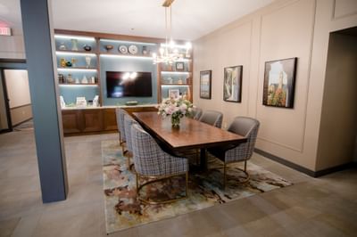 Long wooden conference table with plaid chairs facing the TV screen and wall display shelf at La Tourelle Hotel and Spa