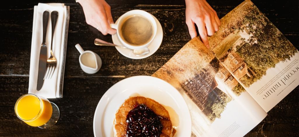 A Person reads a magazine while enjoying breakfast and coffee in Canmore.