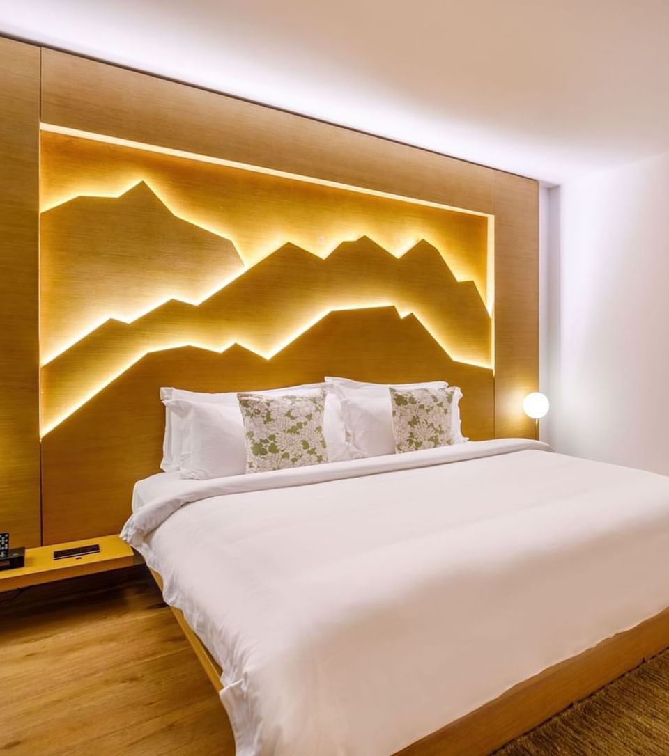 Deluxe Suite bedroom with a backlit mountain headboard and a comfy bed at The Terraces Resort & Spa