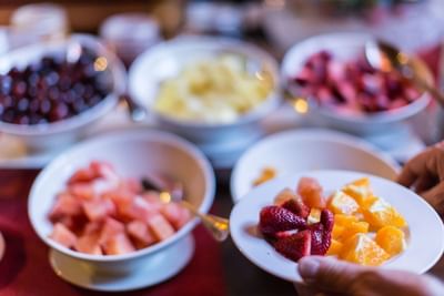 Fruta fresca en bowls junto al plato de un huésped bajo luz suave en buffet de desayuno en NOI Vitacura
