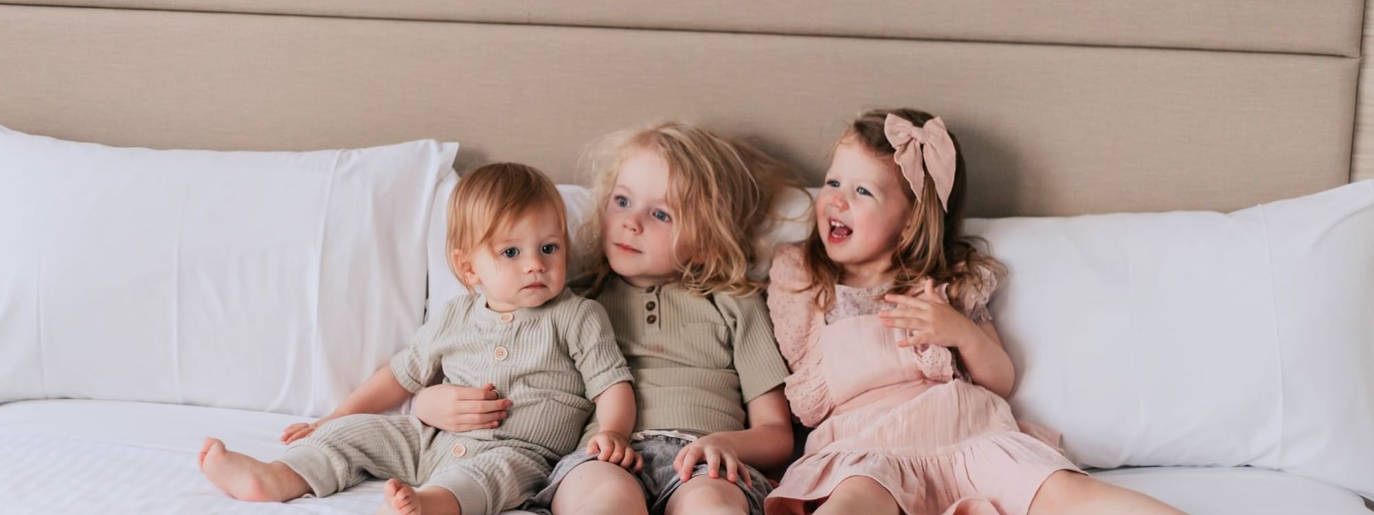 Three children sitting on a bed with PLAYTIME IN PARRAMATTA offer.