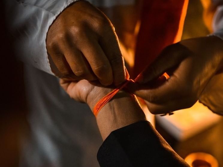 Two hands tie a ceremonial red thread around a wrist during a traditional ritual near Dwarika's Himalayan Wellbeing