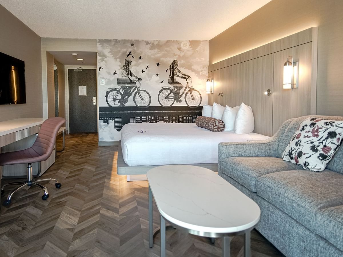 Hotel guestroom with king bed, sofa, work desk, chair, TV, mini fridge, and microwave