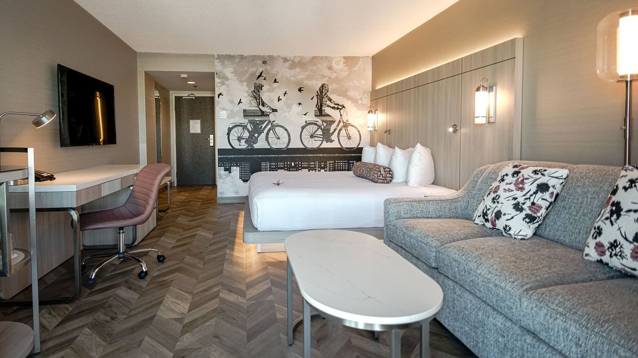 Hotel guestroom with king bed, sofa, work desk, chair, TV, mini fridge, and microwave