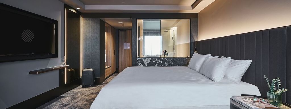 Superior room with king bed, dark upholstered headboard, wall-mounted TV, and modern bathroom at Pullman East Melbourne