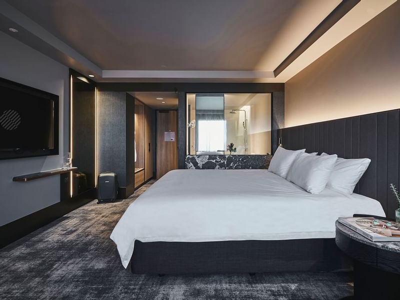 Superior room with king bed, dark upholstered headboard, wall-mounted TV, and modern bathroom at Pullman East Melbourne