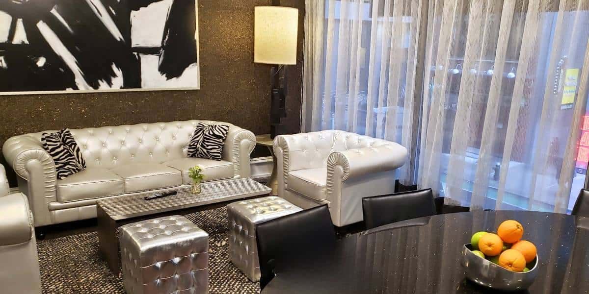 A modern lobby with a white sofa, chair, coffee table, and lamp.