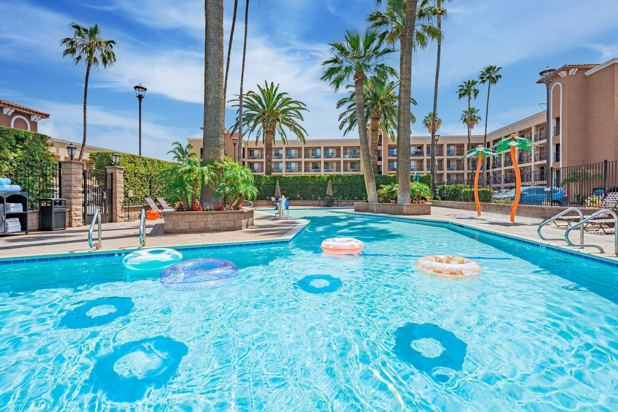 A swimming pool with inflatable floats and palm trees in the background