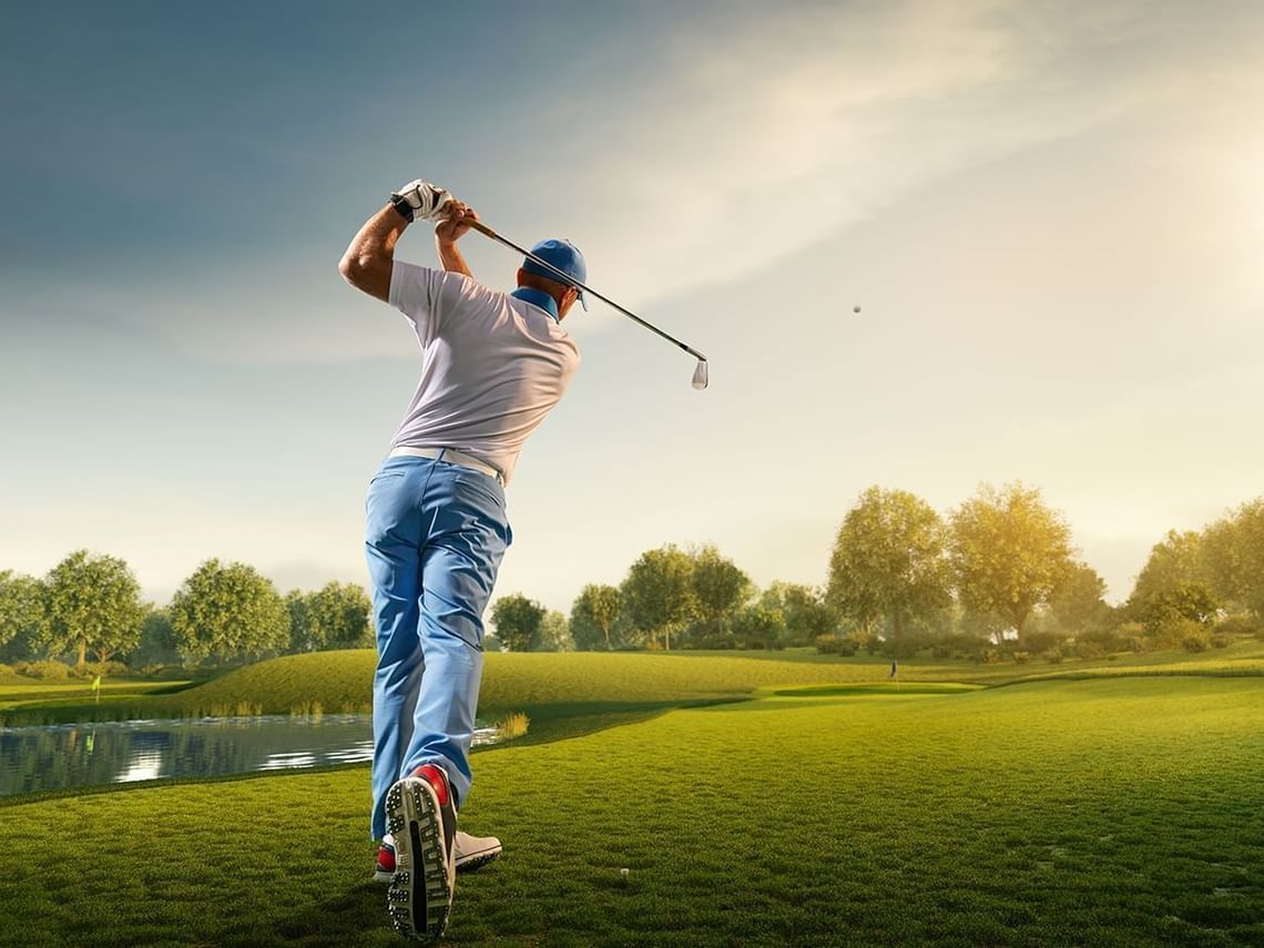 Man swinging a golf club on a lush green field at Rosen Inn Hotels and Resorts