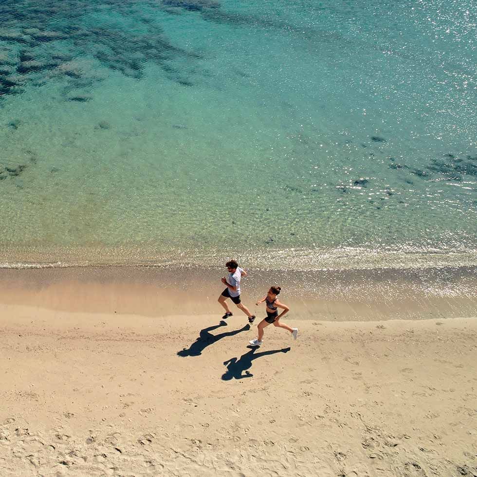 Aerial view of running couple on beach, Falkensteiner Hotels