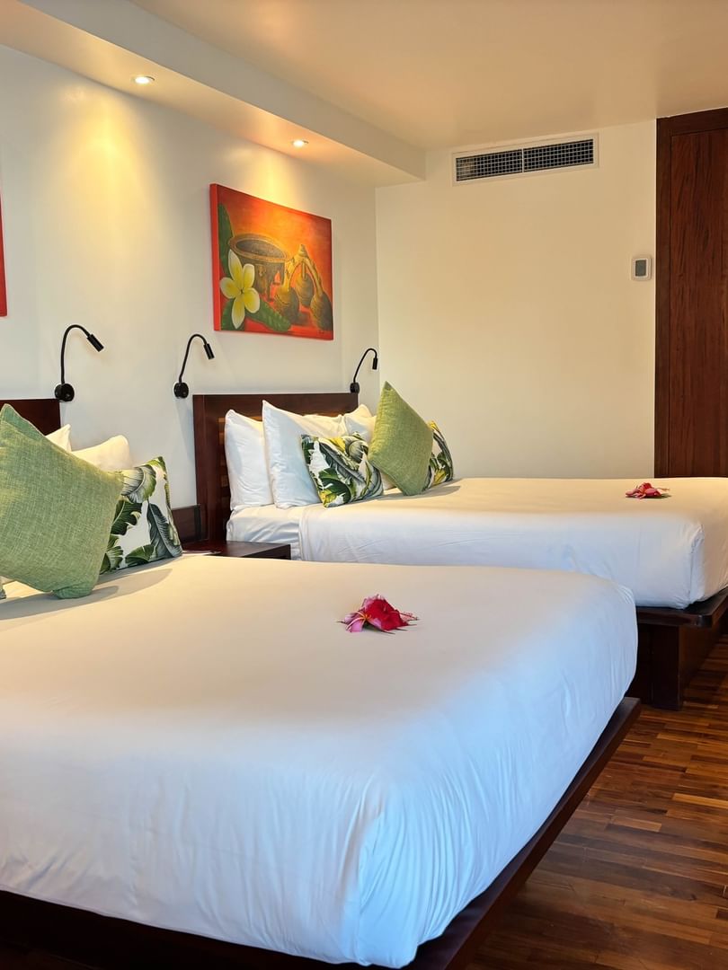 Two double beds with white linens and tropical pillows in Ocean View Room at Warwick Fiji Korolevu.