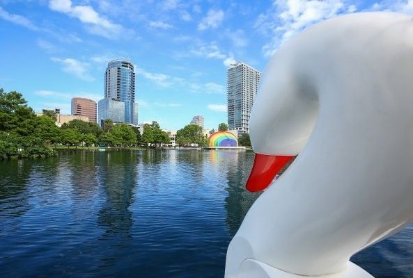 A swan boat gliding alongside cityscape views at Lake Eola Park near Rosen Inn International, a family-friendly hotel near Lake Eola Park in Orlando.