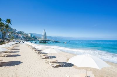 Rows of white umbrellas and lounge chairs on Playa Los Muertos facing the blue ocean waters at Casa Dona Susana