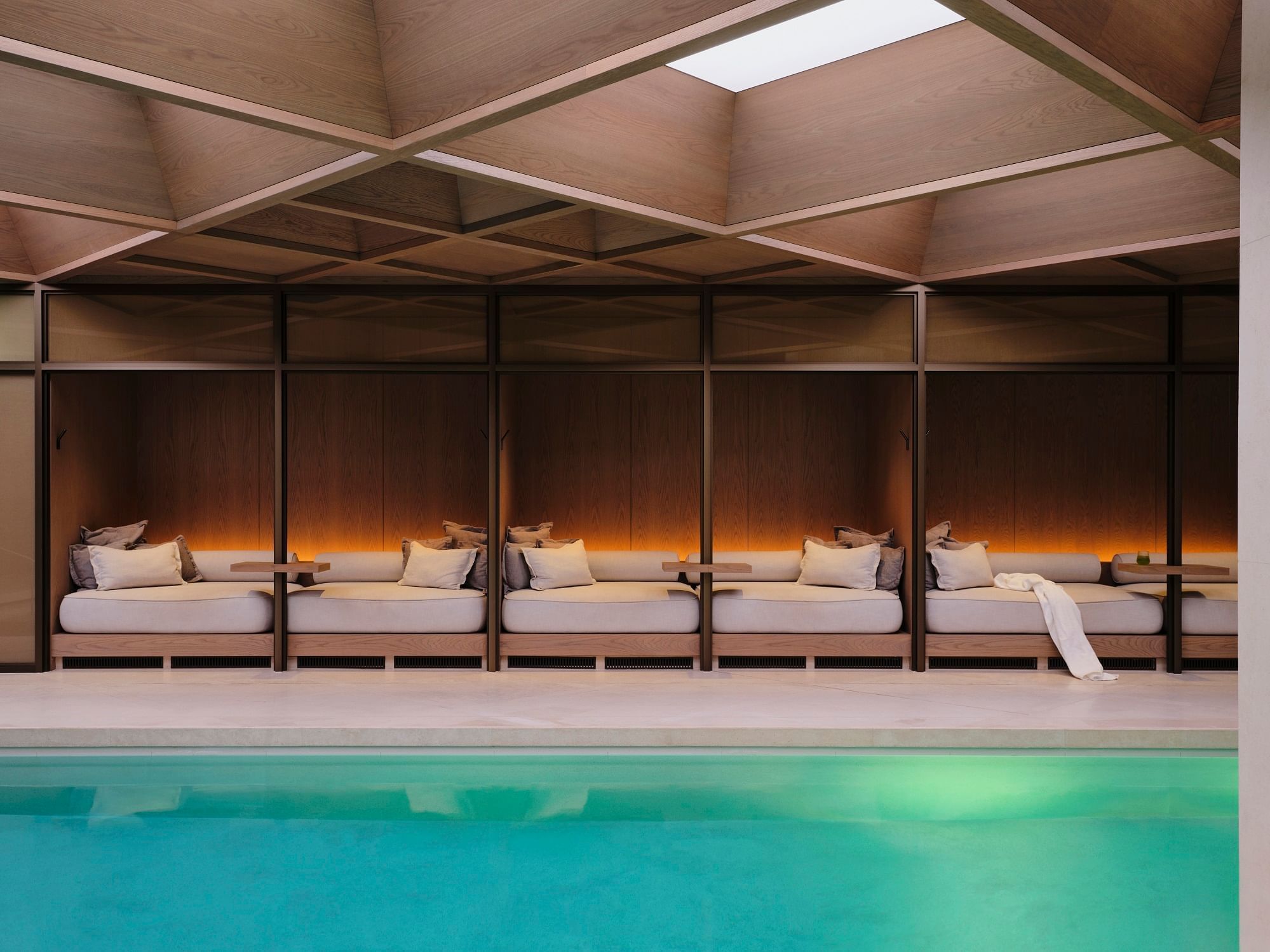 Serene indoor pool area with cozy loungers beneath a distinctive wooden ceiling at The Londoner
