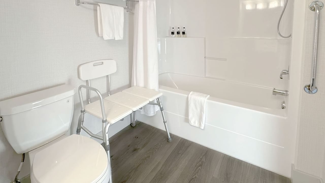 Accessible washroom with toilet, bathtub, soap, and towel