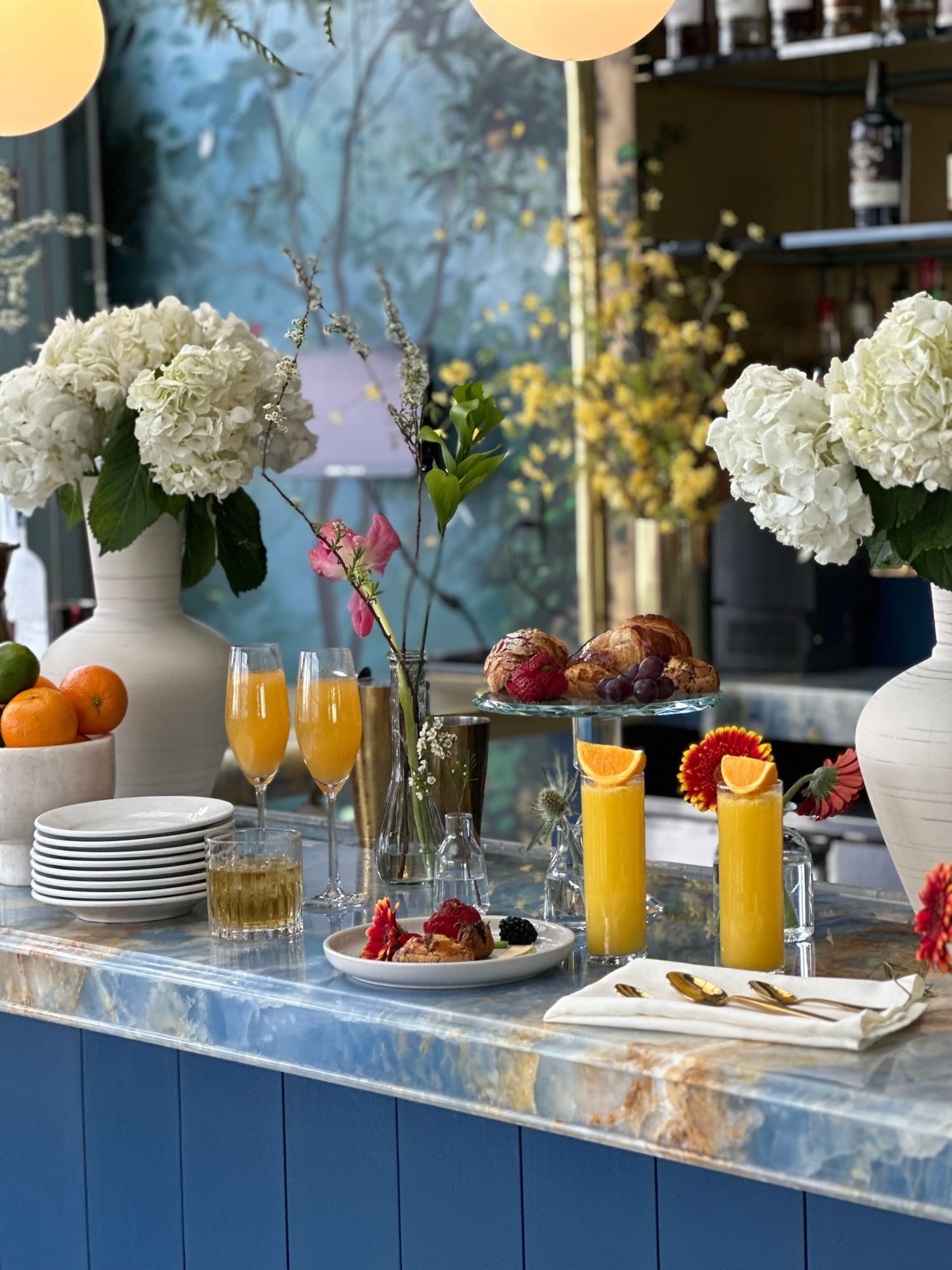An arrangement of orange juice, pastries and florals
