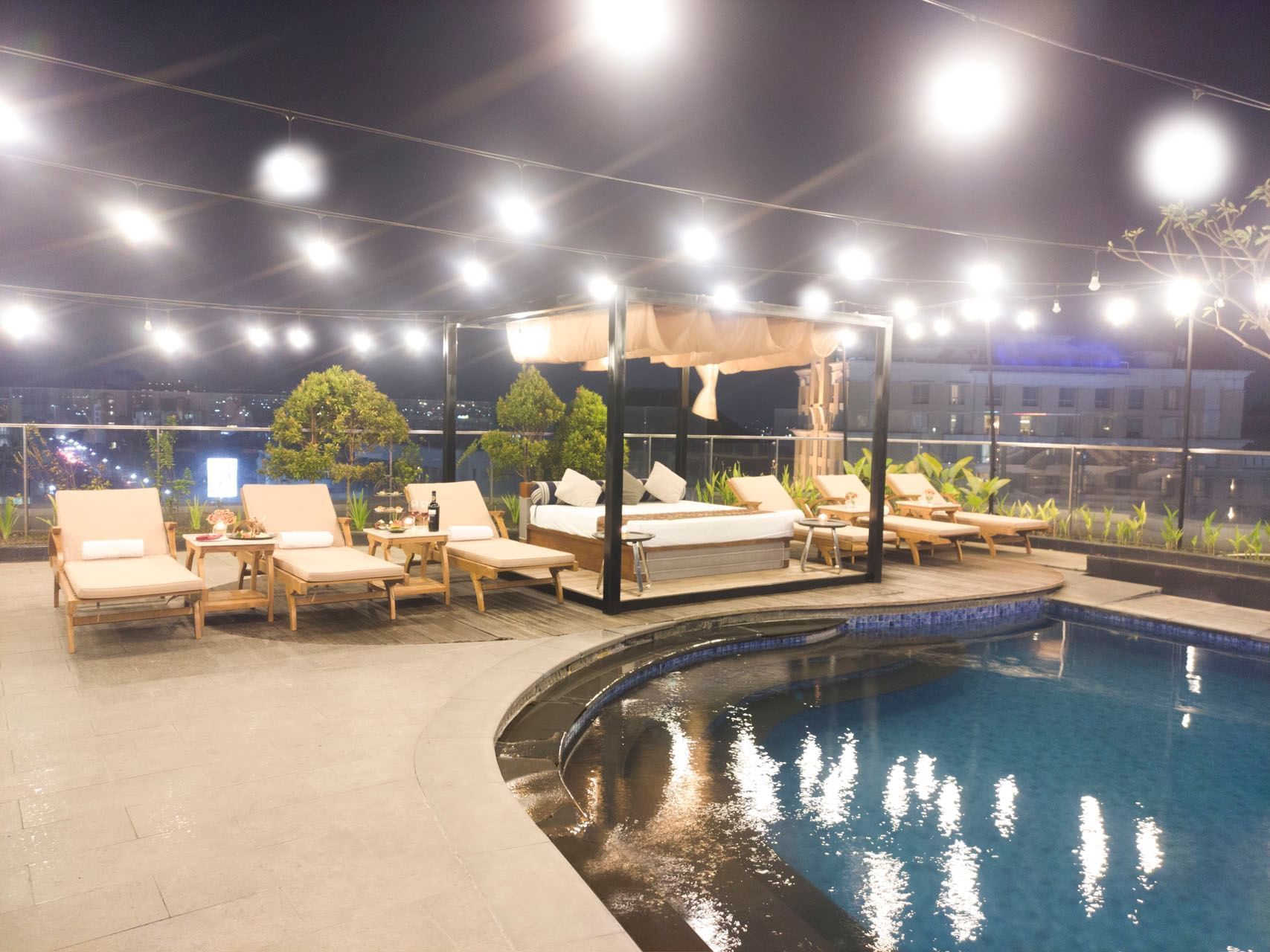 Outdoor pool area with sun loungers and rooftop lights at Po Hotel Semarang